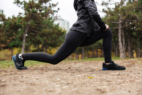 abgeschnittenes Bild eines Fitness-Girls, das sich die Beine streckt - Foto, Bild