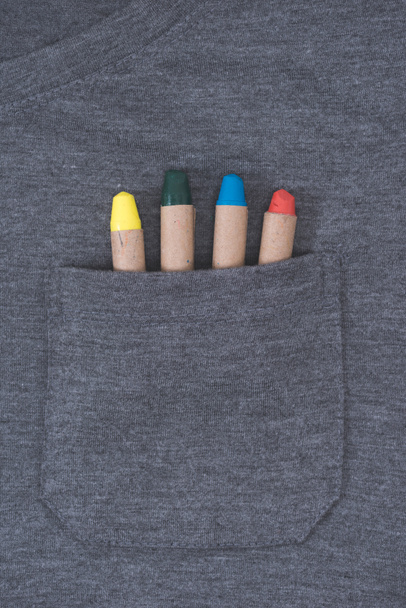 vergrote weergave van grijze mannelijke t-shirt met kleurrijke kleurpotloden in zak - Foto, afbeelding