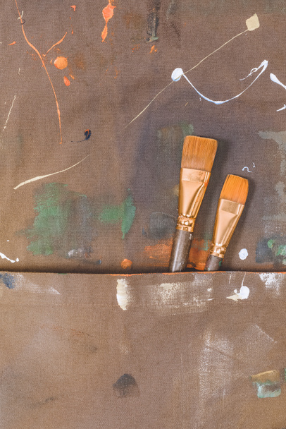 close-up view of brown apron with brushes and paint spots - Photo, Image