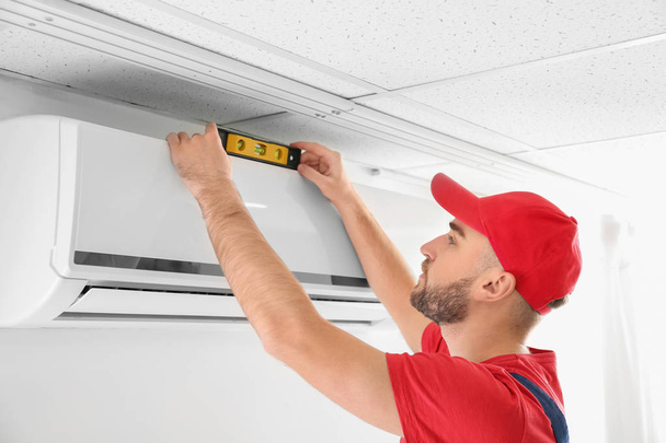 Male technician installing air conditioner indoors - Foto, immagini