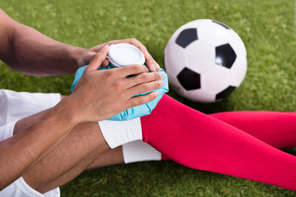 Close-up Of An Injured Male Soccer Player Applying Ice Pack On Knee - Photo, Image