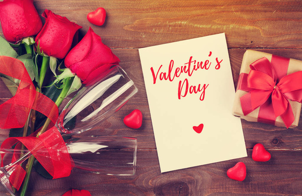 Dia dos Namorados cartão de saudação, caixa de presente e rosas vermelhas na mesa de madeira. Vista superior com espaço de cópia
 - Foto, Imagem