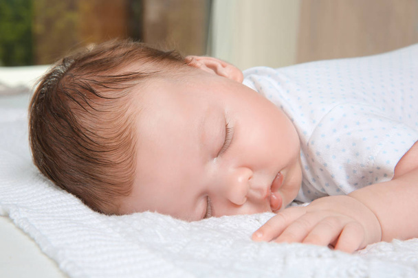 Cute little baby sleeping on plaid at home - Foto, afbeelding