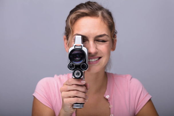 Close-up Of A Smiling Young Woman Looking Through Lens Of Retro Camera - 写真・画像