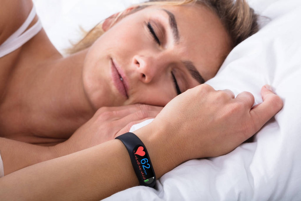 Fitness Activity Tracker With Heartbeat Rate On Woman Hand Over Bed - Фото, изображение