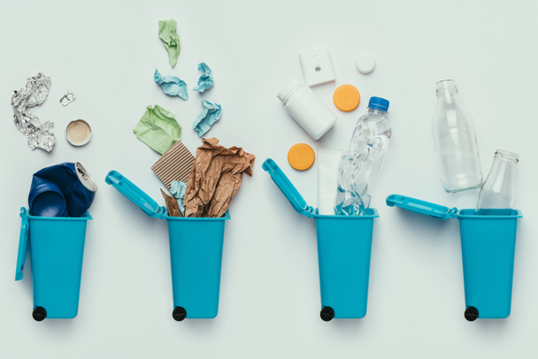 vista superior de contenedores de basura y basura surtida aislada en gris, concepto de reciclaje
 - Foto, Imagen