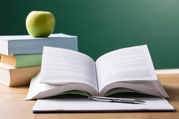 Close-up Of School Textbook On Desk In Front Of Blackboard - Photo, image