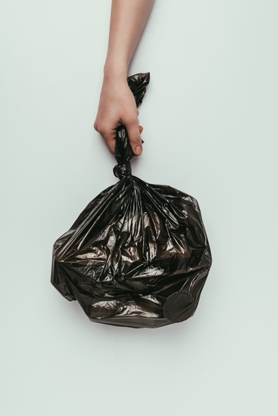 tiro recortado de mujer sosteniendo bolsa de basura en mano aislado en gris
 - Foto, Imagen