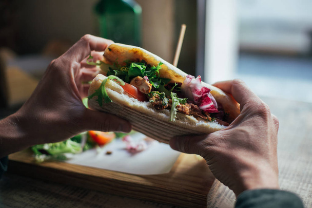 cropped view of man holding sandwich with roasted chicken and arugula salad - Photo, Image