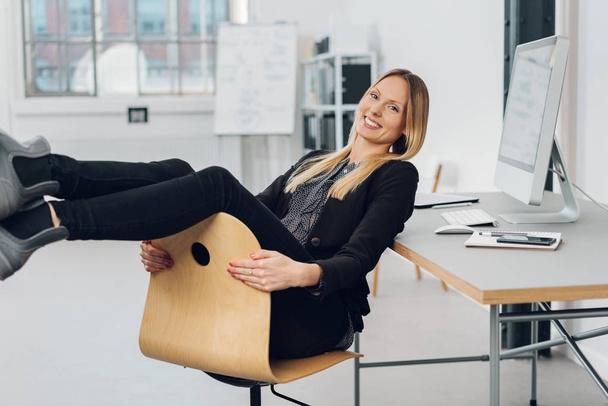businesswoman dangling her legs over chair - Photo, image