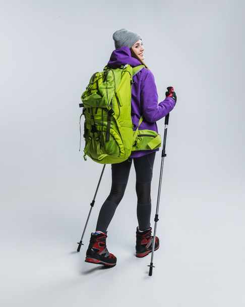beautiful hiker with backpack and hiking sticks, isolated on grey - Photo, Image