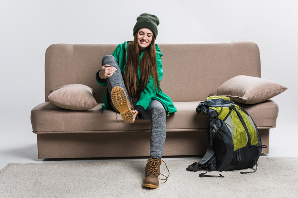 happy girl wearing hiking boots on sofa with backpack - Photo, Image