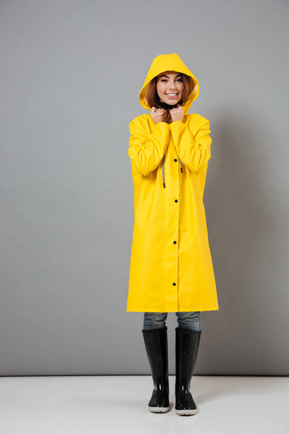 Full length portrait of a smiling girl dressed in raincoat - 写真・画像