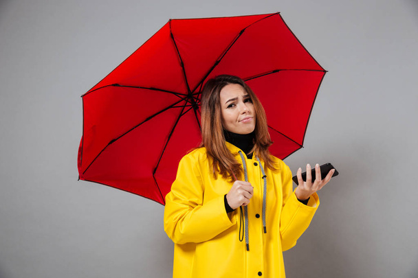 Portrait of an upset girl dressed in raincoat - Foto, afbeelding