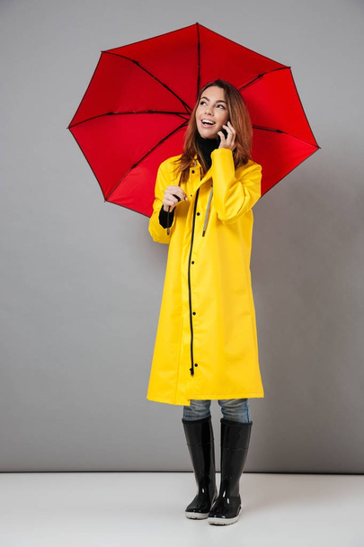 Full length portrait of a cheerful girl dressed in raincoat - Fotó, kép