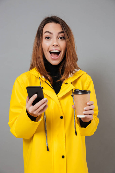 Portrait of a cheerful girl dressed in raincoat - Foto, imagen