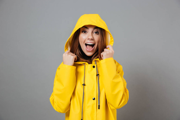 Portrait of a joyful girl dressed in raincoat - 写真・画像