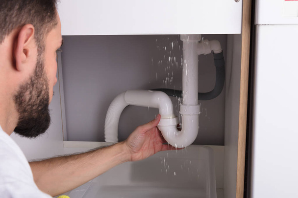 Close-up Of A Man Looking At Sink Pipe Leakage In Kitchen - Photo, Image