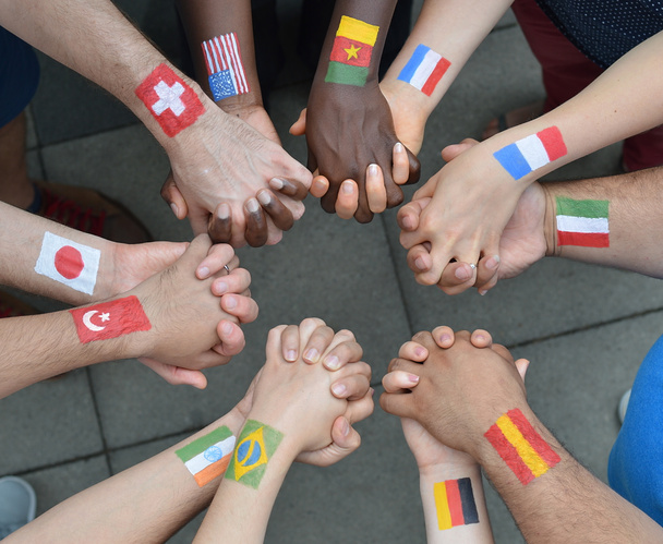 Irmãos e irmãs internacionais de pé em círculo e de mãos dadas com bandeiras pintadas nos braços
 - Foto, Imagem