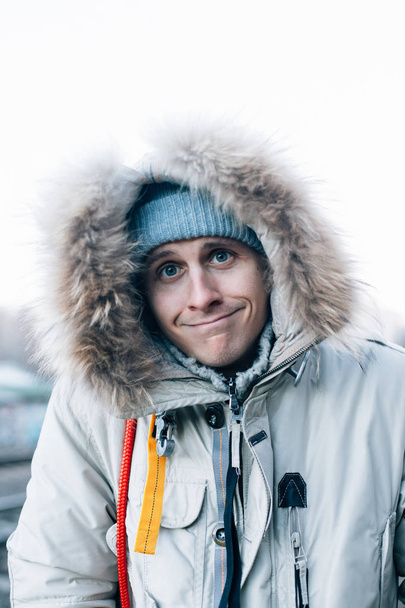 funny Caucasian man in winter jacket and hat looking at camera - Fotó, kép