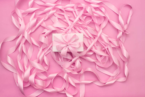 Schachteln mit Geschenken auf dem Hintergrund einer Spule aus dekorativen Satinbändern in rosa Farbe. - Foto, Bild