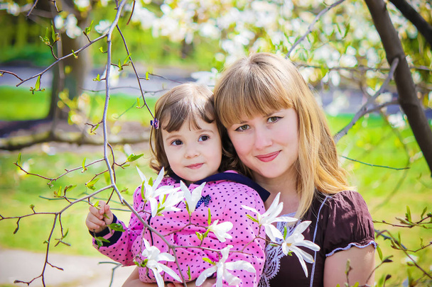 Uma criança e mãe no jardim de magnólia florescente. Foco seletivo
.  - Foto, Imagem