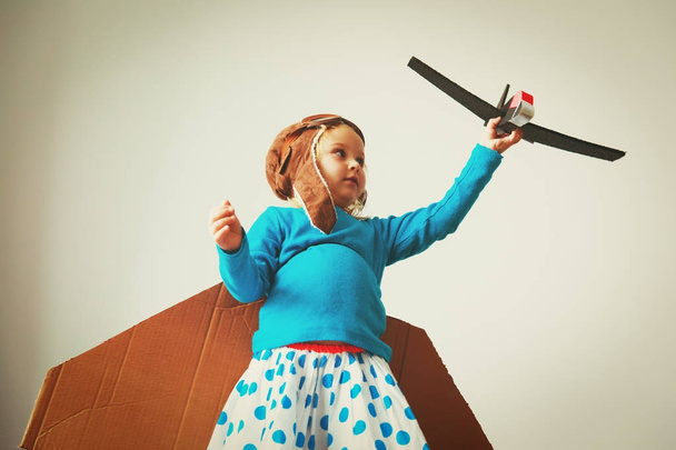 маленька дівчинка з пілотними окулярами і крилами грає літати вдома
 - Фото, зображення