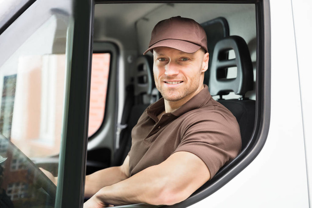 Portrait Of A Happy Young Delivery Man Sitting Inside Van - Foto, afbeelding