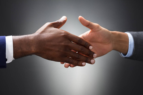 Close-up Of Two People Shaking Hands On Gray Background - Fotografie, Obrázek