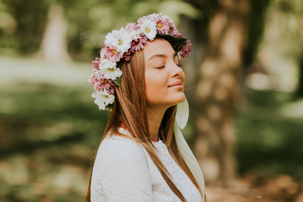 Retrato de mujer joven con corona de flores frescas en la cabeza
 - Foto, imagen