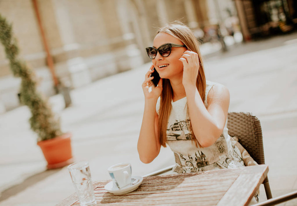 Красивая молодая женщина пользуется мобильным телефоном в кафе
 - Фото, изображение