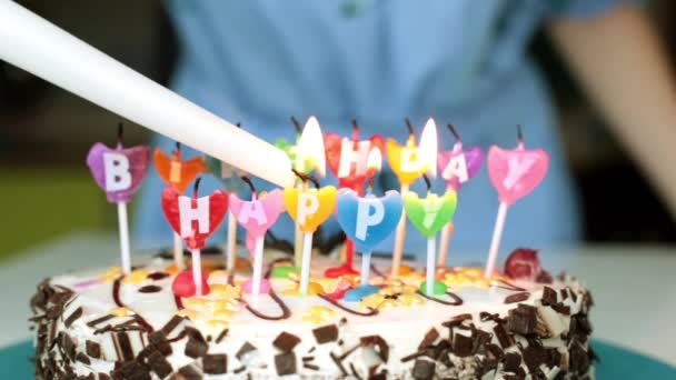 Nainen sytyttää kynttilöitä kakkuun. Syntymäpäivä, loma ja kakku kynttilöillä
. - Materiaali, video
