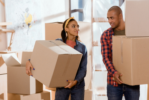 african american couple holding cardboard boxes and moving to new apartment - Photo, Image