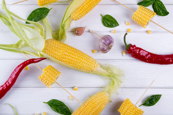 Raw Organic Yellow Corn on the Cob Ready to grill with hot chili pepper garlic and herbs. Mexican Corn. Ideas for barbecue and grill parties. Flat lay. - Фото, изображение