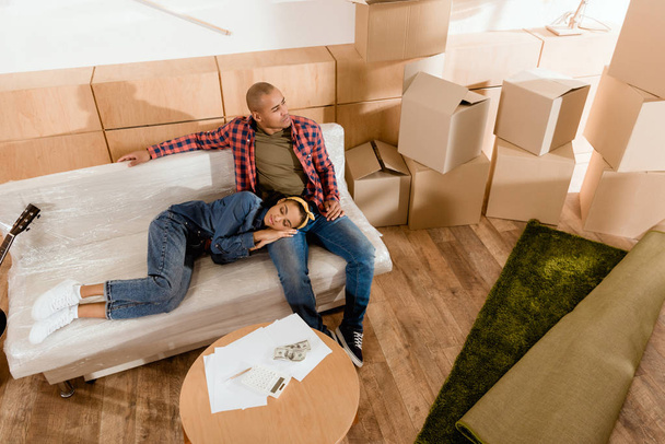 Африканская американская пара отдыхает в новой квартире с картонными коробками
 - Фото, изображение