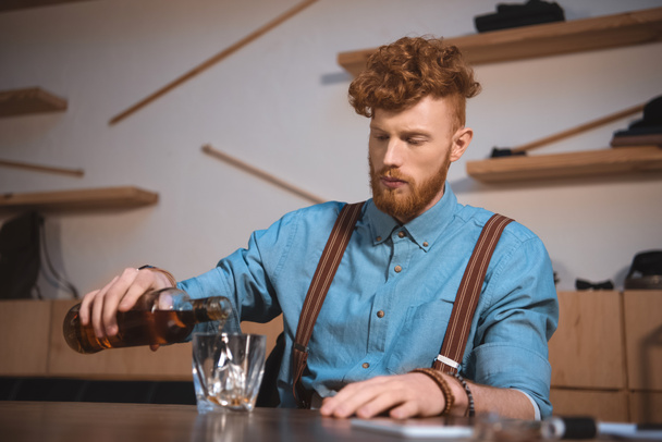 handsome stylish young man pouring whisky from bottle in glass - Foto, Imagem