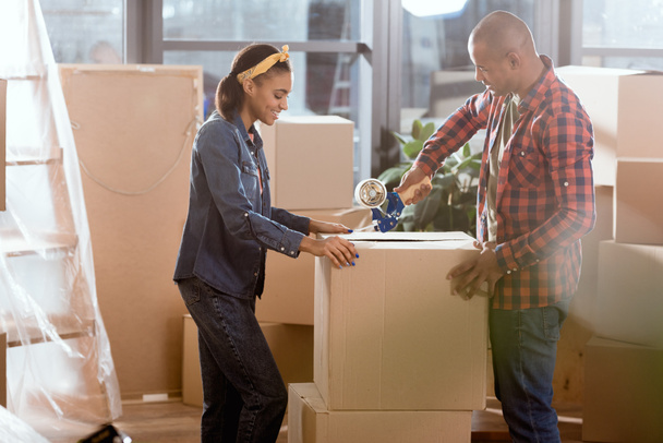 africano americano pareja embalaje caja de cartón para mover en nuevo apartamento
 - Foto, Imagen