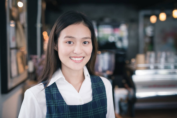 Asian female barista wears blue apron standing in a cafe - Foto, afbeelding