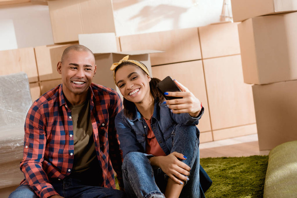 african american couple taking selfie on smartphone in new home - Zdjęcie, obraz