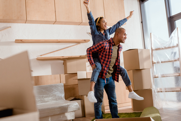 excitada pareja afroamericana montando en nuevo apartamento con cajas de cartón
 - Foto, Imagen