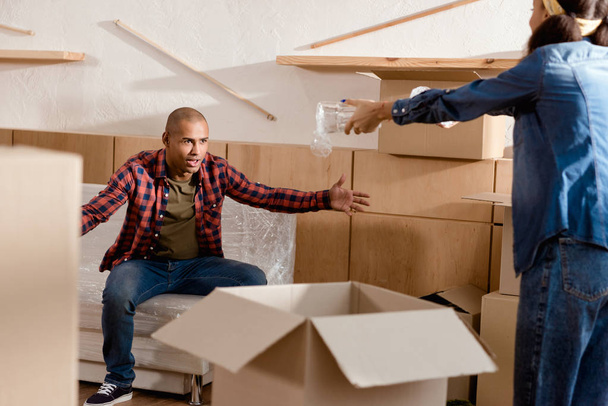 african american couple packing and quarreling in new apartment with cardboard boxes - Photo, Image