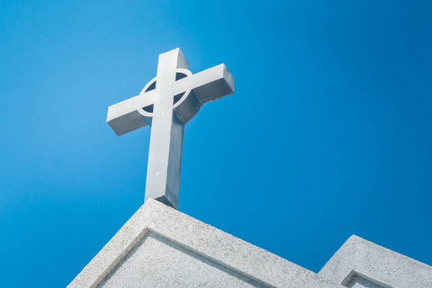 Metal holy cross or crucifix on the top of white church with blue sky in the background. - Photo, Image