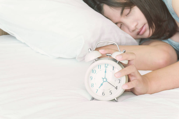 Женщина крупным планом спит на кровати с будильником для пробуждения время
 - Фото, изображение