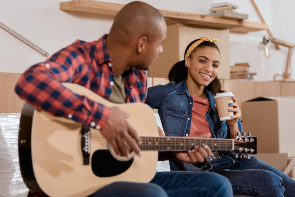 afrikkalainen amerikkalainen pari soittaa akustista kitaraa uudessa kodissa pahvilaatikoilla
 - Valokuva, kuva