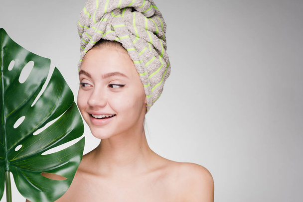 happy smiling girl with a towel on her head holds a green leaf, day spa - Fotoğraf, Görsel
