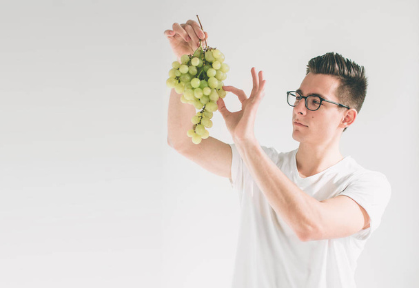 man holding grape, close up. concept. isolated on white. Nerd is wearing glasses. - Foto, Bild
