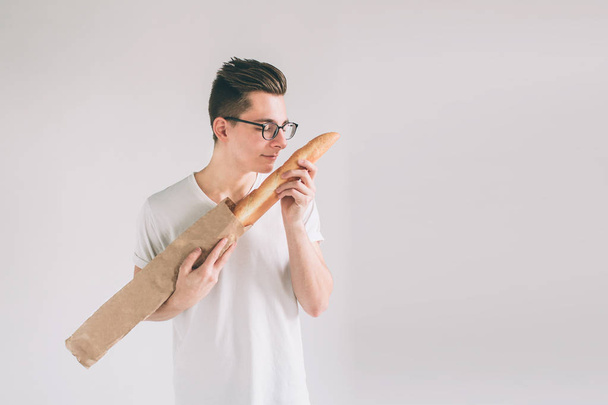 Man with Bread in hand. Freshly baked bread in the hands. .. Nerd is wearing glasses holding a lot of bread in hands isolated on white background - Foto, imagen