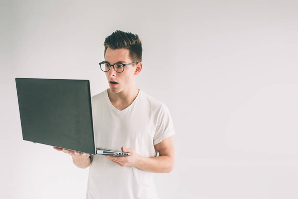 Man holding laptop computer isolated on gray. Nerd is wearing glasses. - Φωτογραφία, εικόνα
