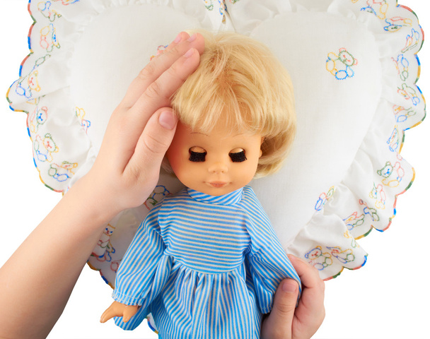 Παιδικά χέρια που κρατούν μια κούκλα που βρίσκεται στο μαξιλάρι - Φωτογραφία, εικόνα