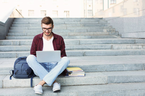 Uśmiechający się student siedząc na schodach przy użyciu laptopa - Zdjęcie, obraz